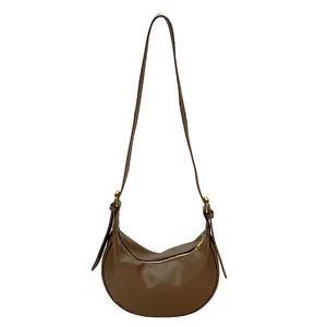 Dark brown leather crescent shoulder bag with pebbled texture and gold zipper