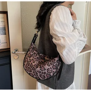 Detailed close-up of leopard print crescent bag with black strap and golden buckle