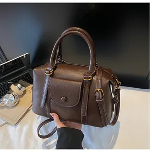 Close-up of vintage brown leather handbag next to laptop and headphones on a desk