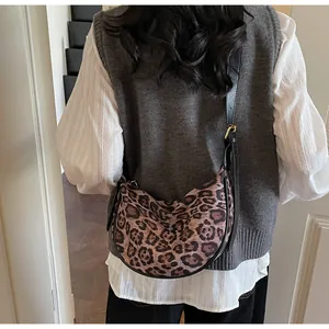 Close-up of leopard print crescent bag with black leather strap and gold buckle