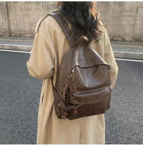 Sac à dos vintage en cuir marron foncé avec breloques chien porté sur un trench beige