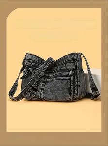 Close-up of vintage black denim shoulder bag with multiple zippers and metal rings