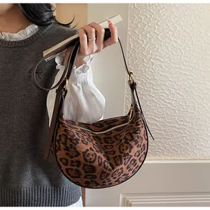 Macro shot of stylish leopard print faux suede hobo bag with gold hardware and leather strap