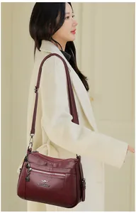 Detail of burgundy pebbled leather handbag with adjustable strap on beige coat model