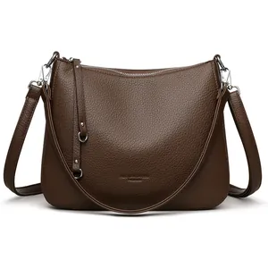 Brown lychee leather crescent shoulder bag with adjustable strap on white background