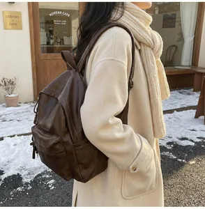 Détail d'un sac à dos vintage en cuir marron café dans un décor d'hiver enneigé