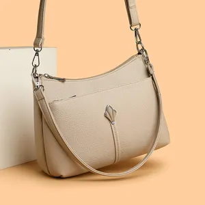 Elegante bolso bandolera de cuero beige con detalles plateados en base decorativa
