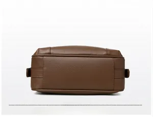 Detail view of the flat rectangular base and stitching of a brown lychee leather bag