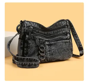 Detailed view of dark gray denim shoulder bag with multi-pocket design and metal D-rings