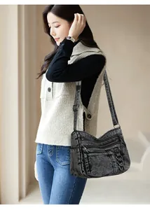 Detail of vintage black washed denim shoulder bag with multiple functional zip pockets