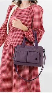 Detail of purple nylon crossbody bag with dual front flap pockets and adjustable strap