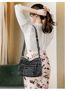 Model wearing a vintage washed black denim crossbody bag with multiple zip pockets