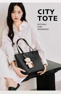 Modern black oversized tote bag with plush bear charm styled in a minimalist city setting