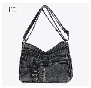 Detail view of black vintage denim crossbody bag with multiple zippers and metal rings