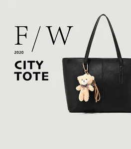 Close-up of black textured tote bag featuring a beige plush bear charm with bow