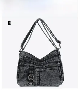 Front detail of vintage washed denim crossbody bag featuring multiple zipper pockets