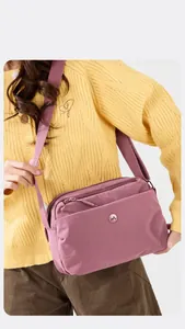 Detail der rosafarbenen Nylon-Umhängetasche mit Doppelreißverschluss und Gurtband