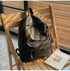Gros plan du sac à dos rétro en similicuir noir avec logo sur une chaise en bois