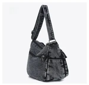 Side view of washed charcoal denim shoulder bag with metal zippers and vintage texture