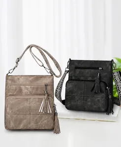 Detail of khaki and black crossbody bags with stylish tassels and woven straps