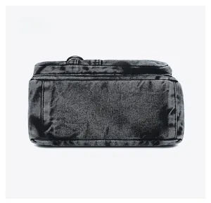 Detail view of the bottom of this dark washed denim bag showing stitching and texture