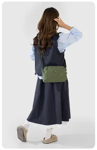 Detail der grünen Nylon-Umhängetasche mit verstellbarem Gurt am Model-Outfit