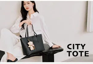 Detail of black pebbled leather tote bag with stylish plush bear charm on strap