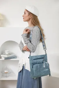Detailed close-up of light blue quilted crossbody bag with embroidered strap and tassel