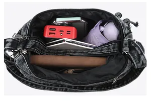 Detail view showing large interior capacity and compartments of the denim shoulder bag