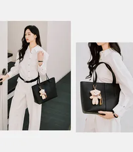 Detailed view of a black leather tote bag with a cute bear pendant for daily commuting use