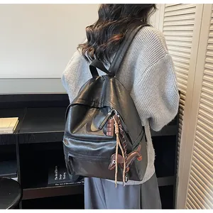 Détail d'un sac à dos vintage en cuir PU noir avec breloques chiot et carré de chocolat