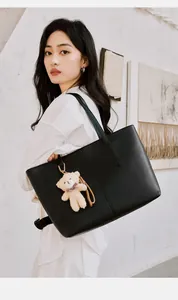 Large black leather tote bag with a cute plush bear pendant on an Asian model