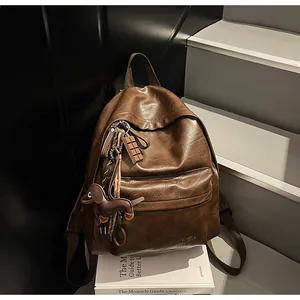 Détail d'un sac à dos rétro en similicuir marron foncé avec breloque chien et logo