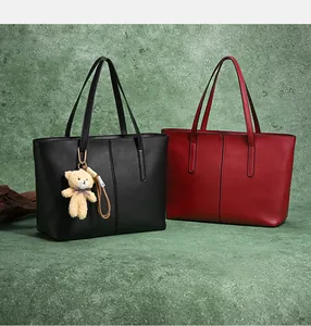 Detailed close-up of large tote bags in matte black and red leather with bear charm