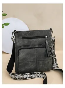 Close-up of retro dark gray bucket bag featuring leather tassels and ethnic embroidered strap