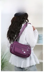 Detail of purple oxford crossbody bag showing multiple functional zipper compartments