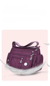 Detail of purple oxford crossbody bag with quilted diamond pattern and multi-zipper pockets
