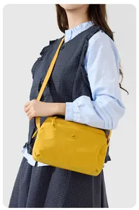 Detailansicht der gelben Nylon-Umhängetasche mit rundem Logo und verstellbarem Schultergurt