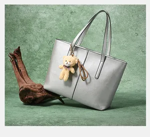 Detail of silver matte tote bag with vertical stitching and cute plush bear charm