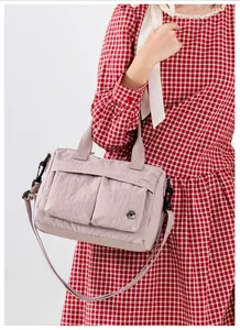 Detail of lavender nylon shoulder bag with multiple pockets and silver brand logo
