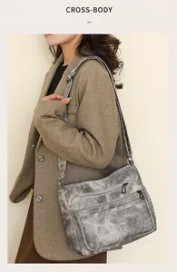 Détail du sac à bandoulière en cuir souple gris avec plusieurs compartiments zippés