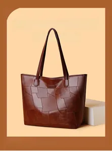 Close-up of irregular patchwork design on dark reddish-brown faux leather tote bag