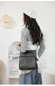 Detail of dark gray crossbody bag with fringe tassel and wide jacquard strap