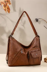 Close-up of brown PU leather bag featuring diagonal zipper and flap pocket details