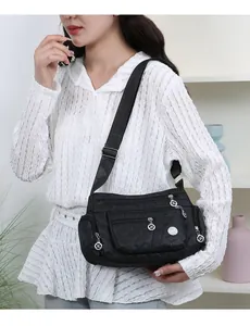 Detailed view of black quilted nylon crossbody bag with multiple zipper pockets and XL logo