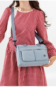 Light blue nylon crossbody bag featuring double front flap pockets on a checkered dress model