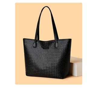 Detail of black woven leather tote bag with classic geometric texture and logo patch