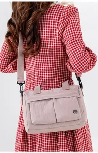 Detailed view of light pink nylon crossbody bag with multi-pockets worn by a model