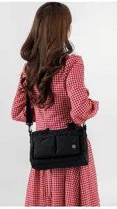 Macro detail of lightweight black nylon handbag with double front pockets and adjustable strap