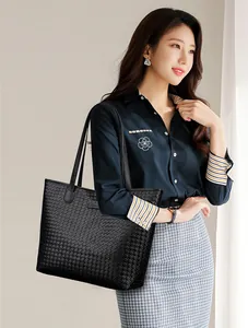 Close-up of black woven texture on synthetic leather tote bag with metallic logo